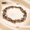 Antique gold floral bracelet with red, green, and blue gemstones on a white background