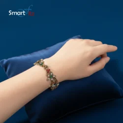 Antique gold floral bracelet with red, green, and blue gemstones on a white background