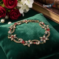 Antique gold floral bracelet with red, green, and blue gemstones on a white background