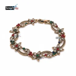 Antique gold floral bracelet with red, green, and blue gemstones on a white background